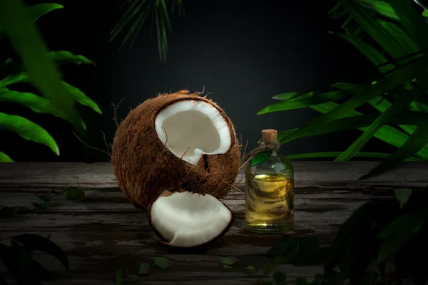 Крупным планом вид приятный свежий кокосовый и нефть на фоне зеленых листьев — стоковое фото